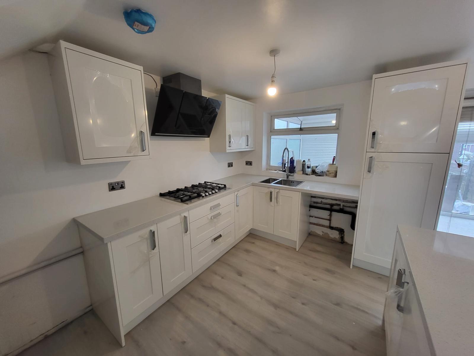 Modern kitchen with white cabinets, gas stove, and refrigerator.